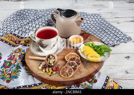 Teiera blu in ghisa. Bastoncini di cannella, nome, fettine di limone e zenzero essiccato su un tagliere. Ancora vita. Set di tè in ghisa con diverse erbe f Foto Stock