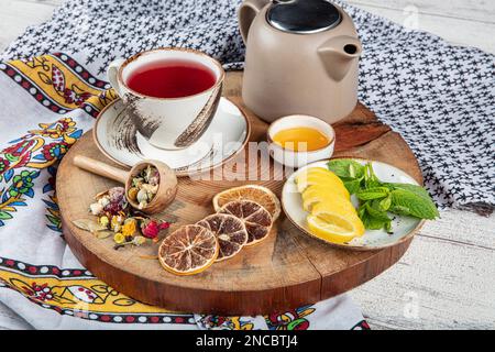 Teiera blu in ghisa. Bastoncini di cannella, nome, fettine di limone e zenzero essiccato su un tagliere. Ancora vita. Set di tè in ghisa con diverse erbe f Foto Stock