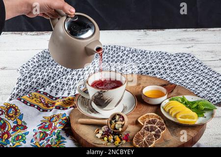 Teiera blu in ghisa. Bastoncini di cannella, nome, fettine di limone e zenzero essiccato su un tagliere. Ancora vita. Set di tè in ghisa con diverse erbe f Foto Stock