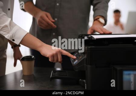 Dipendenti che utilizzano una stampante moderna in ufficio, in primo piano Foto Stock
