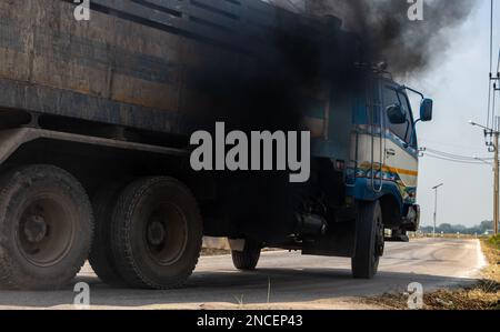 Un carrello carico viaggia su strada con fumo nero spesso proveniente dallo scarico Foto Stock