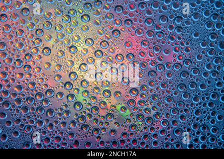 Goccioline d'acqua sul tavolo di vetro con luci colorate sullo sfondo Foto Stock