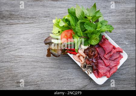 carne di manzo cruda taglia fette su piatto bianco e verdure fresche carne fresca vista dall'alto - sashimi di manzo, fegato di manzo cibo asiatico tailandese Foto Stock