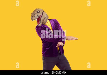 Uomo che indossa una maschera di dinosauro che balla su sfondo giallo Foto  stock - Alamy