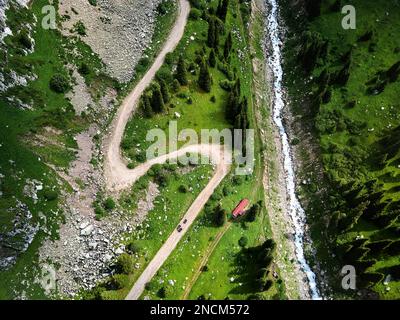 Splendido scenario della strada di ghiaia montagne e fiume con verde collina in Almaty, Kazakistan. Outdoor e concetto di trekking, drone aereo top down shot Foto Stock