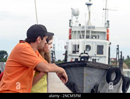 Coppia uomo e donna che si trovano in posizione inclinata sulla ringhiera del traghetto sullo sfondo del rimorchiatore della nave sul fiume a Novosibirsk . Foto Stock