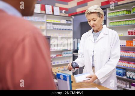 Farmacia, scansione del codice a barre e farmacista donna senior con cliente che acquista farmaci e pillole. Pagamento in negozio, clinica farmaceutica e operatore sanitario Foto Stock