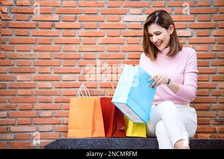 Felice giovane donna guarda nei sacchetti di shopping. Foto Stock