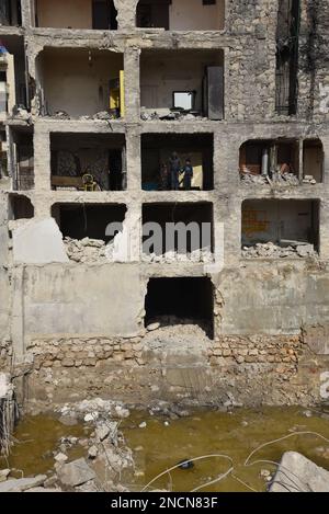 Saleppo, Siria. 13th Feb, 2023. Ali Abdul-Rahman e i suoi due figli stanno sul lato del suo portico distrutto nella sua casa nel quartiere di Masharqa nella città di Aleppo, Siria settentrionale, 13 febbraio 2023. Mucchi di detriti del terremoto hanno dato ad Ali Abdul-Rahman, un sopravvissuto nel nord della Siria, un duro flashback al secondo vicino-morte quando è sfuggito ad un muro fatiscente in casa, e come il muro condiviso da due edifici ha tenuto gli amici e vicini parte. PER ANDARE CON 'caratteristica: Come un muro in Siria Aleppo separa la vita dalla morte in tragico terremoto' Credit: Monsef Memari/Xinhua/Alamy Live News Foto Stock