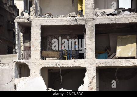 Saleppo, Siria. 13th Feb, 2023. Ali Abdul-Rahman e i suoi due figli stanno sul lato del suo portico distrutto nella sua casa nel quartiere di Masharqa nella città di Aleppo, Siria settentrionale, 13 febbraio 2023. Mucchi di detriti del terremoto hanno dato ad Ali Abdul-Rahman, un sopravvissuto nel nord della Siria, un duro flashback al secondo vicino-morte quando è sfuggito ad un muro fatiscente in casa, e come il muro condiviso da due edifici ha tenuto gli amici e vicini parte. PER ANDARE CON 'caratteristica: Come un muro in Siria Aleppo separa la vita dalla morte in tragico terremoto' Credit: Monsef Memari/Xinhua/Alamy Live News Foto Stock