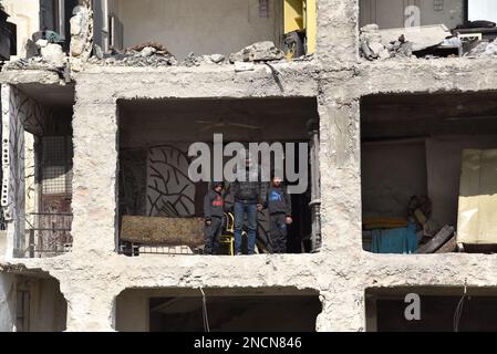 Saleppo, Siria. 13th Feb, 2023. Ali Abdul-Rahman e i suoi due figli stanno sul lato del suo portico distrutto nella sua casa nel quartiere di Masharqa nella città di Aleppo, Siria settentrionale, 13 febbraio 2023. Mucchi di detriti del terremoto hanno dato ad Ali Abdul-Rahman, un sopravvissuto nella Siria settentrionale, un duro flashback alla seconda morte, quando è scappato da un muro fatiscente a casa, e come il muro condiviso da due edifici ha tenuto amici e vicini parte.PER ANDARE CON 'Feature: Come un muro in Aleppo Siria separa la vita dalla morte in tragico terremoto' credito: Monsef Memari/Xinhua/Alamy Live News Foto Stock