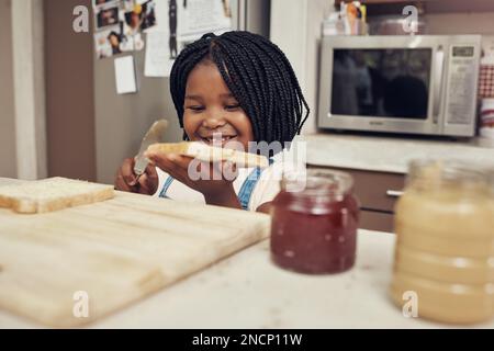 Questo sarà gustoso e delizioso. una adorabile bambina che fa il pranzo per se stessa in cucina a casa. Foto Stock