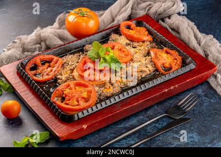 Un primo piano di piatto di Lahm Sainiah a base di carne e pomodori su un vassoio di legno Foto Stock