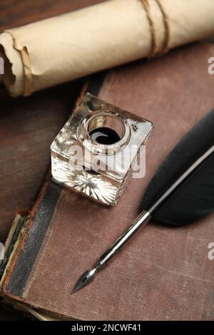 Penna piuma, Inkwell, vecchio libro e pergamena su tavola di legno, primo piano Foto Stock