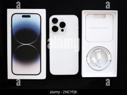 Isolato su sfondo nero nuovo iPhone 14 pro in colore argento con una tripla fotocamera, scatola e un filo per caricare il dispositivo. Foto Stock