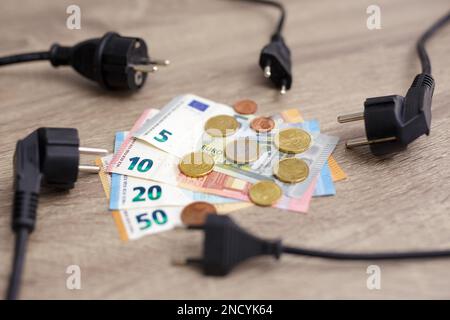 concetto di energia elettrica costosa - primo piano delle prese elettriche e delle banconote e monete europee Foto Stock