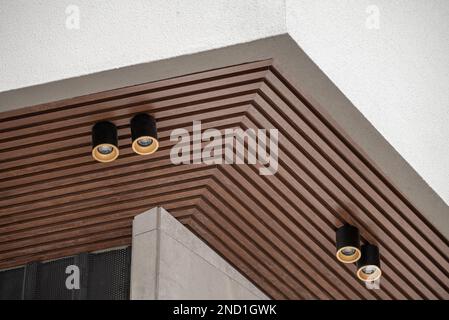 Pannello da soffitto in PVC rivestito in vinile simile al legno con illuminazione moderna su di esso Foto Stock