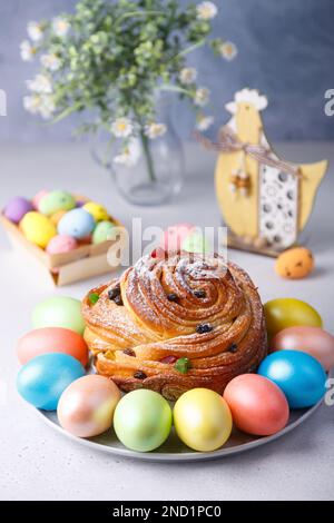 Craffin (Cruffin) con uvetta e canditi cosparsi di zucchero a velo. Tradizionale pane di Pasqua Kulich e uova dipinte su sfondo grigio Foto Stock