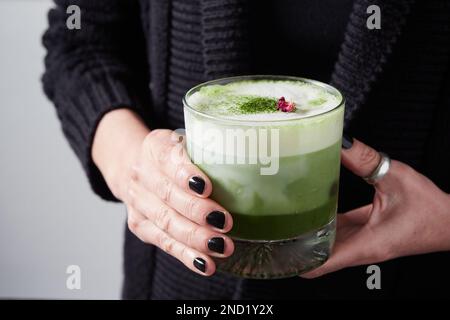 Donna irriconoscibile con bicchieri di cocktail matcha verde con latte Foto Stock