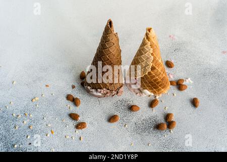 Coni di waffle rovesciati con gelato su fondo in cemento Foto Stock