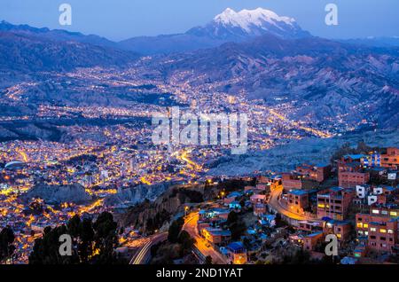 Veduta aerea della città illuminata con case residenziali situate sul pendio di montagna in serata in Bolivia Foto Stock