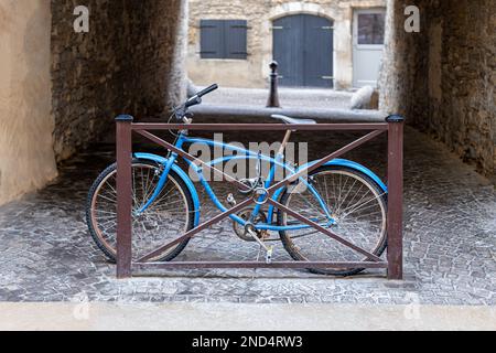 Vecchia bicicletta blu chiusa in strada vicino alla recinzione arrugginita di metallo Foto Stock