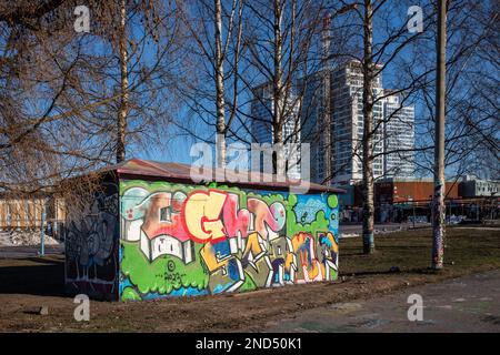 Street art. Graffite colorata su una sottostazione con alti edifici Kalasatama sullo sfondo nel quartiere Suvilahti di Helsinki, Finlandia. Foto Stock