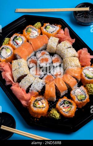 foto molti tipi diversi di sushi, zenzero, wasabi, bastoncini di sushi di legno, salsa di soia che si trova intorno Foto Stock