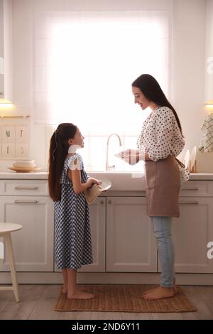 Madre e figlia puliscono insieme i piatti in cucina Foto Stock