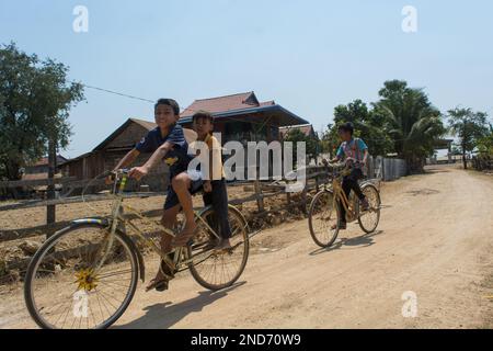 I bambini di Phuong Pheun si divertono con le biciclette. Pheun è un uomo riuscito nell'allevamento del pollo. Alleva pollo, mucche e maiali per la vendita. Lui Foto Stock