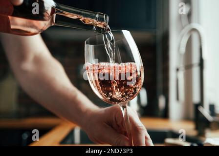 Uomo con bottiglia di vino e bicchieri in cucina Foto Stock