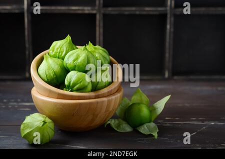 Tomatillos freschi biologici verdi (Physalis philadelphica) con una buccia su un tavolo rustico di legno. Foto Stock