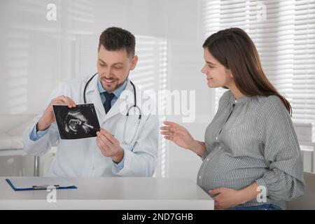 Ginecologo che mostra l'immagine ecografica a una donna in gravidanza in clinica Foto Stock