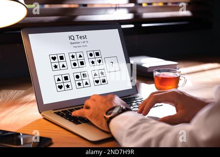 Uomo che utilizza un computer portatile per eseguire il test IQ in ambienti chiusi, primo piano Foto Stock