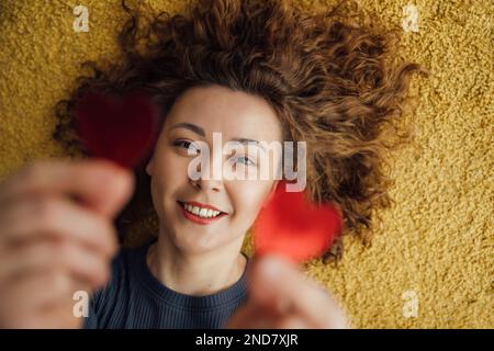 Primo piano ritratto di una donna sorridente che tiene due cuori Foto Stock