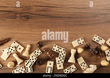 Composizione piatta di pezzi di scacchi e dominali su tavolo di legno, spazio per il testo. Giochi da tavolo Foto Stock