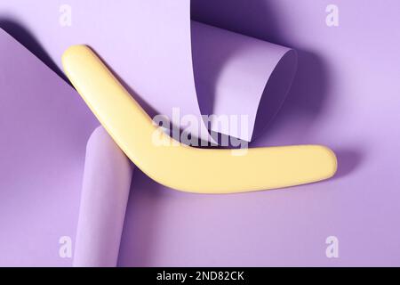Composizione creativa con boomerang in legno giallo su sfondo lilla Foto Stock
