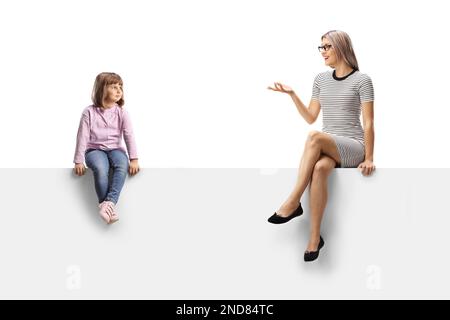 Bambina seduta su un pannello vuoto e ascoltando una donna che parla isolato su sfondo bianco Foto Stock