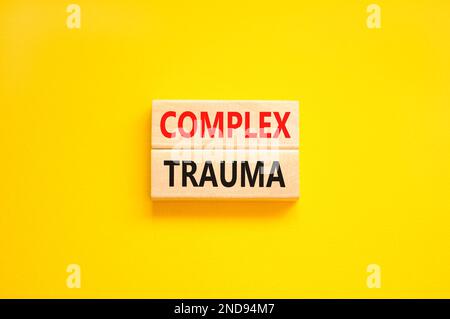 Simbolo di trauma complesso. Concetto parole trauma complesso su blocco di legno. Bella tavola giallo sfondo giallo. Psicologia aziendale complesso trauma conc Foto Stock