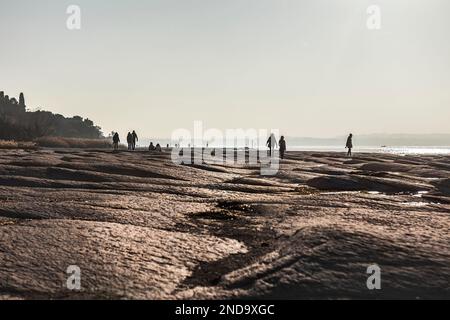 Uno splendido paesaggio naturale al tramonto, caratterizzato da una piacevole passeggiata lungo la pittoresca costa di Sirmione. Le silhouette del Foto Stock