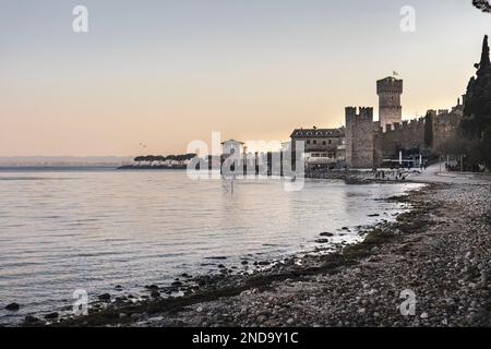 Una splendida vista del Castello di Sirmione al tramonto arroccato su una collina, che domina le acque turchesi del Lago di Garda e la pittoresca costa del Foto Stock