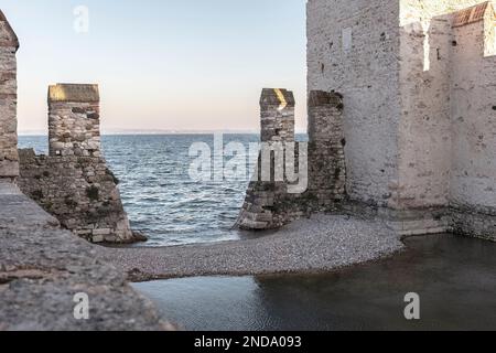 Una splendida vista sul Castello di Sirmione arroccato su una collina, che domina le acque turchesi del Lago di Garda e la pittoresca costa dei dintorni Foto Stock