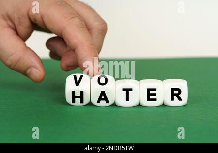 Su una superficie verde sono i cubi bianchi con l'iscrizione - ELETTORE o HATER. Due cubi vengono premuti con un dito. Concetto aziendale. Foto Stock