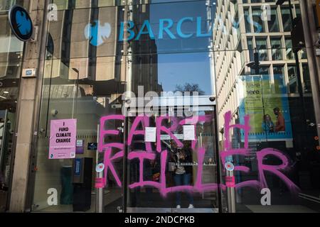 I sostenitori del cambiamento climatico dipingono Graffiti 'Earth Killer' sulla Barclays Bank, filiale di Tottenham Court Road, Londra, febbraio 2023. Ribellione di estinzione. Foto Stock