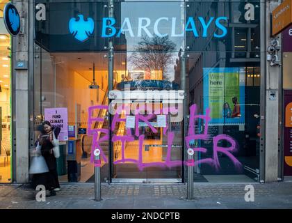 I sostenitori del cambiamento climatico dipingono Graffiti 'Earth Killer' sulla Barclays Bank, filiale di Tottenham Court Road, Londra, febbraio 2023. Ribellione di estinzione. Foto Stock