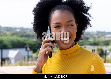 Felice afroamericana businesswoman camminare e parlare su smartphone Foto Stock