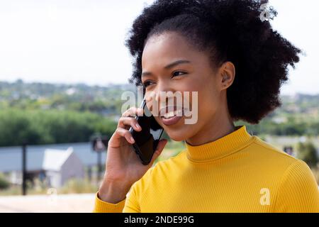 Felice afroamericana businesswoman camminare e parlare su smartphone Foto Stock