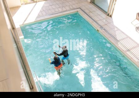Vista aerea di una coppia afroamericana senior che nuota insieme nella piscina. stile di vita e concetto di vita senior in pensione Foto Stock