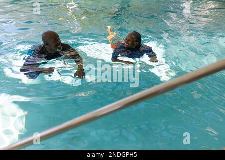 Coppia afroamericana senior che nuota insieme nella piscina. stile di vita e concetto di vita senior in pensione Foto Stock