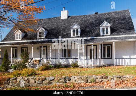 Vecchia facciata ristrutturata della casa Manoir Gourdeau degli anni '1650, con finitura rugosa bianca e finiture blu acciaio in autunno. Foto Stock